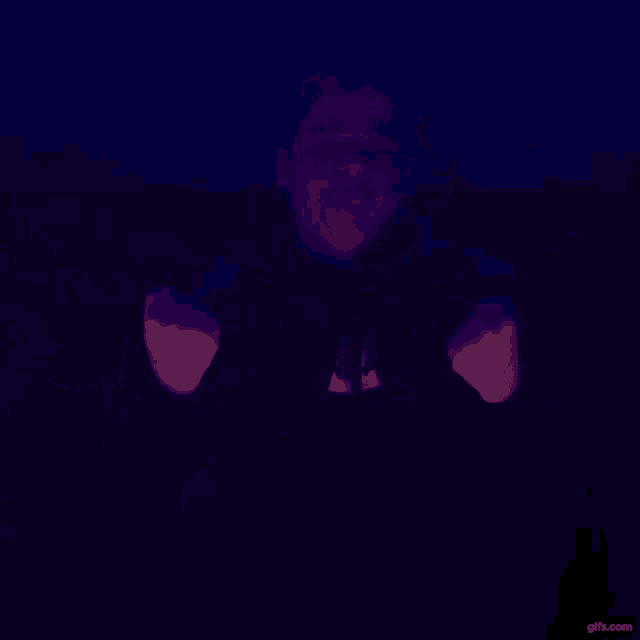 a man is dancing in a dark room with a blue light behind him