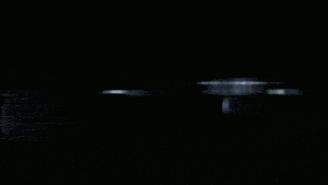 two cars are driving down a street at night with a sign in the background that says ' a '