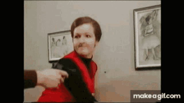 a woman in a red vest is being held by a man in a room with pictures on the wall .