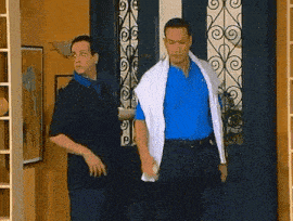 two men are standing in front of a door and one has a towel around his neck
