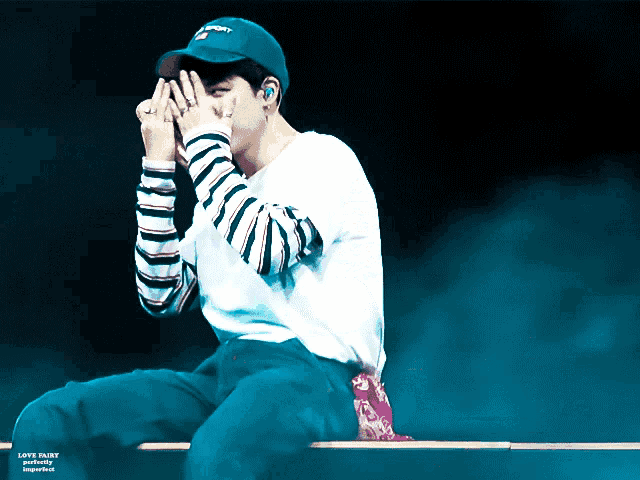 a man wearing a blue hat with the word army on it covering his face