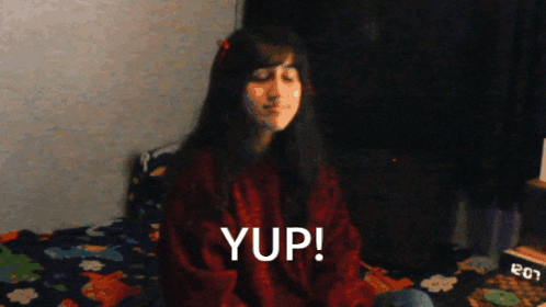 a girl in a red sweater says yup in front of a digital clock