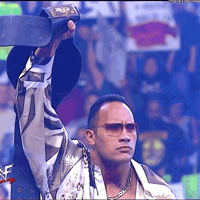 a man wearing sunglasses holds a trophy in his hand in front of a crowd