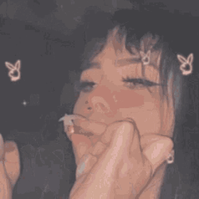a girl is smoking a cigarette and blowing smoke out of her mouth .