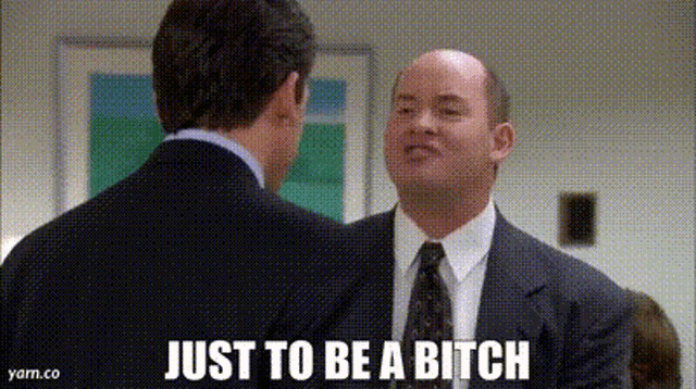 two men in suits and ties are talking to each other . one of the men is saying `` just to be a bitch '' .