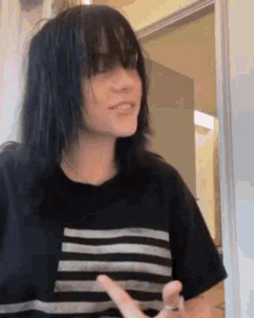 a woman with black hair and bangs is wearing a black and white striped t-shirt .