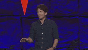 a man speaking into a microphone on a stage with a blue background
