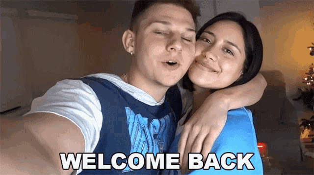 a man and woman are posing for a selfie and the words welcome back are on the screen