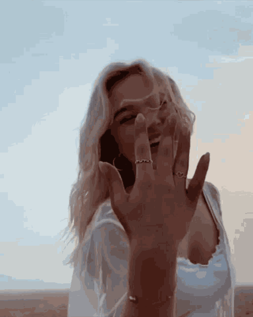 a woman wearing rings on her fingers is making a funny face