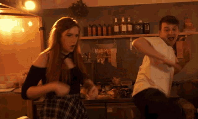a man and a woman are dancing in front of a shelf with bottles on it