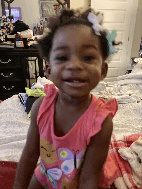 a little girl in a pink shirt with butterflies on it
