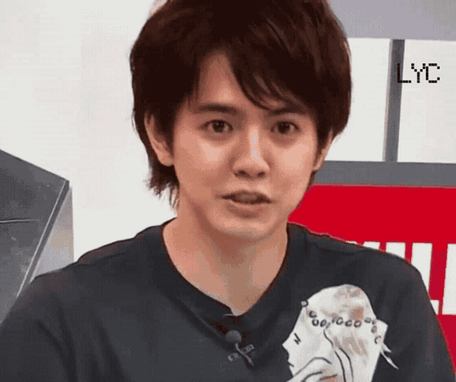 a young man wearing a black shirt with a bird on it looks at the camera