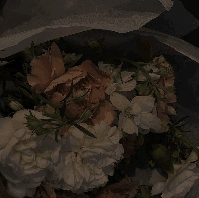 a bunch of flowers are wrapped in tissue paper in a dark room