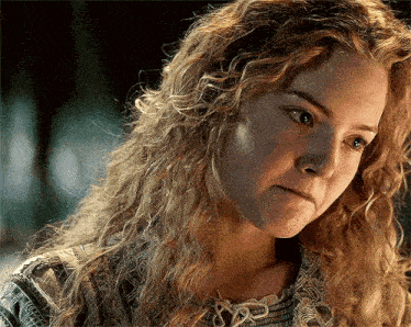 a close up of a woman 's face with long curly hair