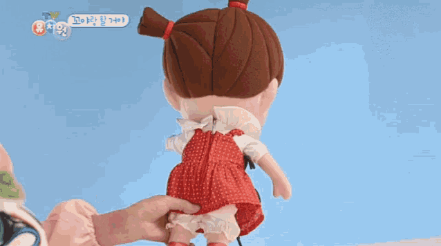 a doll with a bug on her shoulder is being held by a person