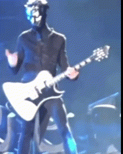 a man wearing a mask is playing a guitar on a stage