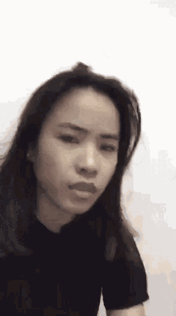 a woman in a black shirt is making a funny face and looking at the camera .