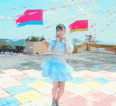a woman in a blue dress stands in front of a yellow boat that says malituan