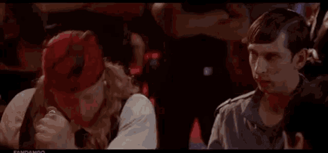 a man wearing a red bandana is fighting another man in a room .