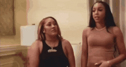 two women are standing next to each other in a room and talking to each other .
