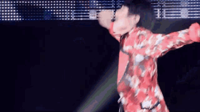 a man in a red and white floral shirt is dancing on a stage .