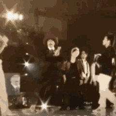 a group of people are standing on a stage in a dark room with a picture of a man in the background .
