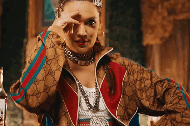 a woman wearing a gucci jacket covering her eyes