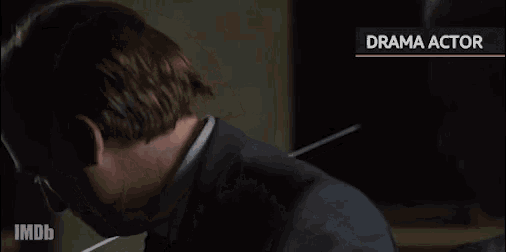 a man in a suit and tie is sitting in a dark room with his eyes closed .