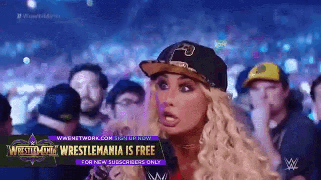 a woman in a baseball cap stands in front of a sign that says wrestlemania is free for new subscribers only