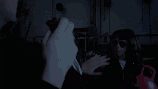 a man is holding a knife in front of a woman in sunglasses