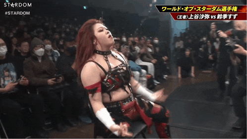 a female wrestler stands in front of a crowd with the word stardom on the bottom left