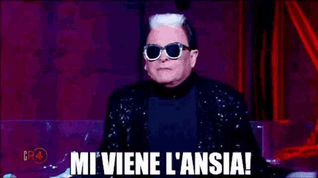 a man wearing sunglasses and a black jacket is making a funny face and saying `` mi viene l ' ansia ''
