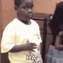 a young boy in a yellow shirt is standing in front of a woman and making a funny face .