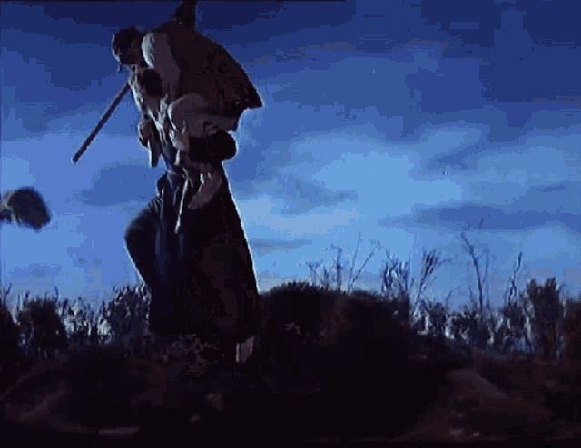 a man is carrying a woman on his back in a field with a blue sky in the background