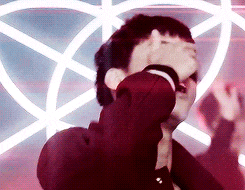 a man is covering his face with his hands in front of a pentagram