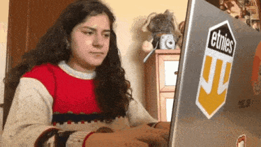 a girl is typing on a laptop with a sticker on it that says ethics