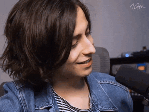 a close up of a person wearing a striped shirt and a blue denim jacket