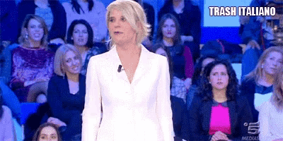 a woman in a white suit is standing in front of a crowd of people and says trash italiano .