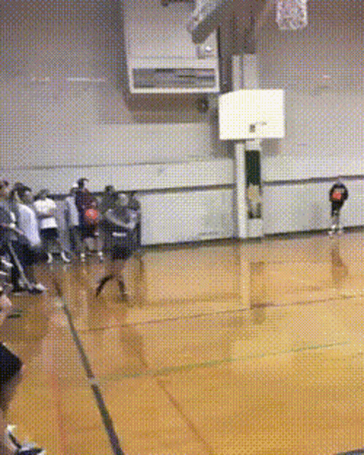 a basketball game is being played in a gym with people watching
