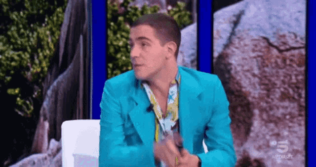 a man in a blue suit is sitting in front of a camera on a television show .