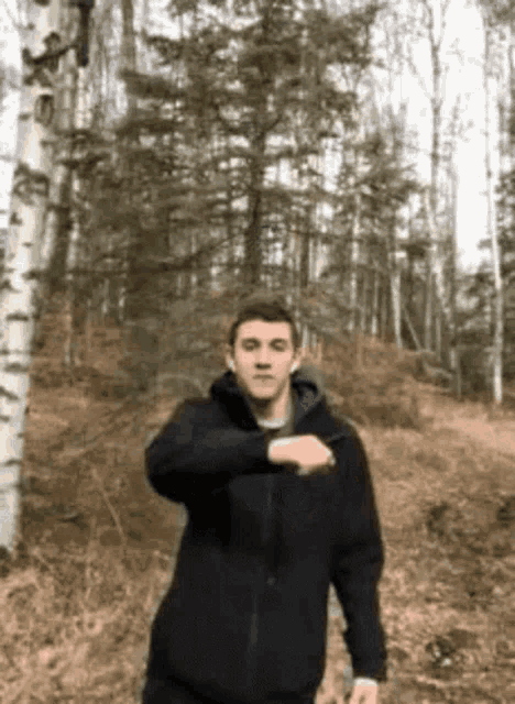 a man wearing a black jacket is standing in the woods