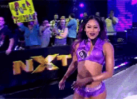 a woman in a purple outfit stands in front of a sign that says next