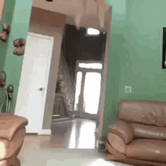 a living room with a brown leather couch and a green wall