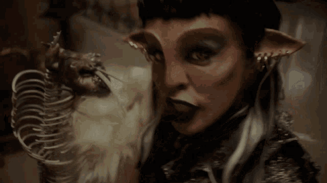 a close up of a woman 's face with a skeleton in her hand