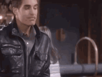 a man in a leather jacket is standing in front of a woman and saying it 's private .