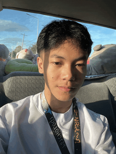 a young man in a car with a lanyard around his neck that says ' poloh12 ' on it