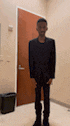 a man in a black suit is standing in front of a door .