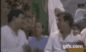 a group of men are standing around talking to each other in a room .