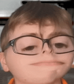 a young boy wearing glasses making a funny face .