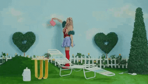 a woman is watering a plant with a watering can in a garden .